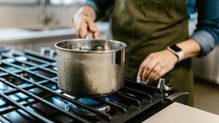 Pot of water being taken off the stove 