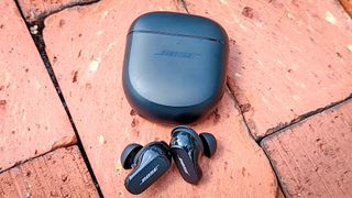 Bose QuietComfort Earbuds 2 in black with charging case placed on brick paving