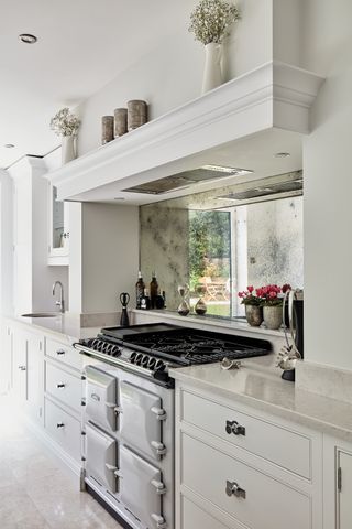 with white cabinetry aga and mirrored backsplash
