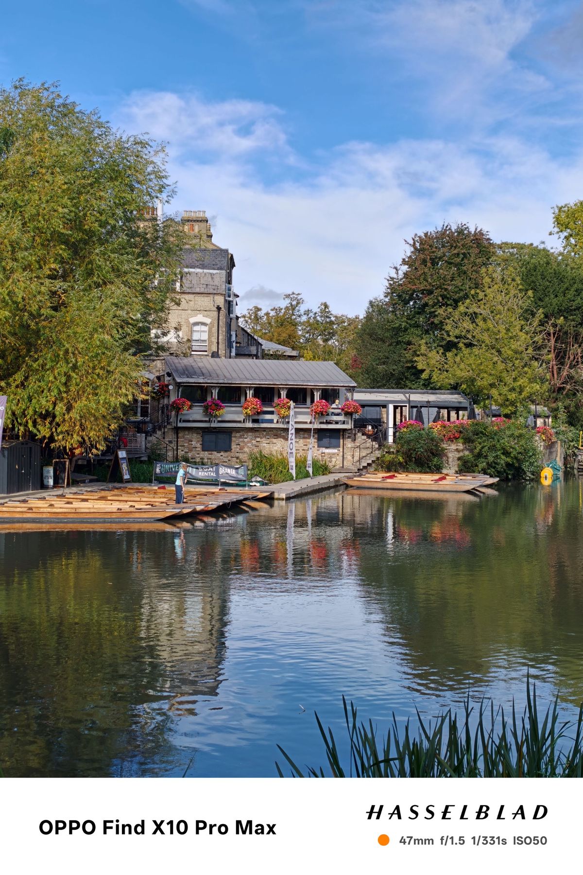Riverside buildings and wooden punts reflected in calm water.
