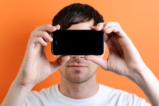 Man holding a mobile phone in front of his face