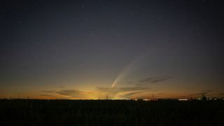 A photo of a bright comet with a long tail shining in the night sky