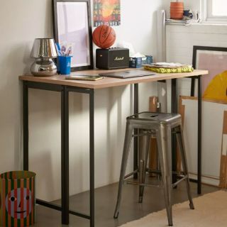 office nook with standing desk, stool, laptop and pictures; gives off an industrial look