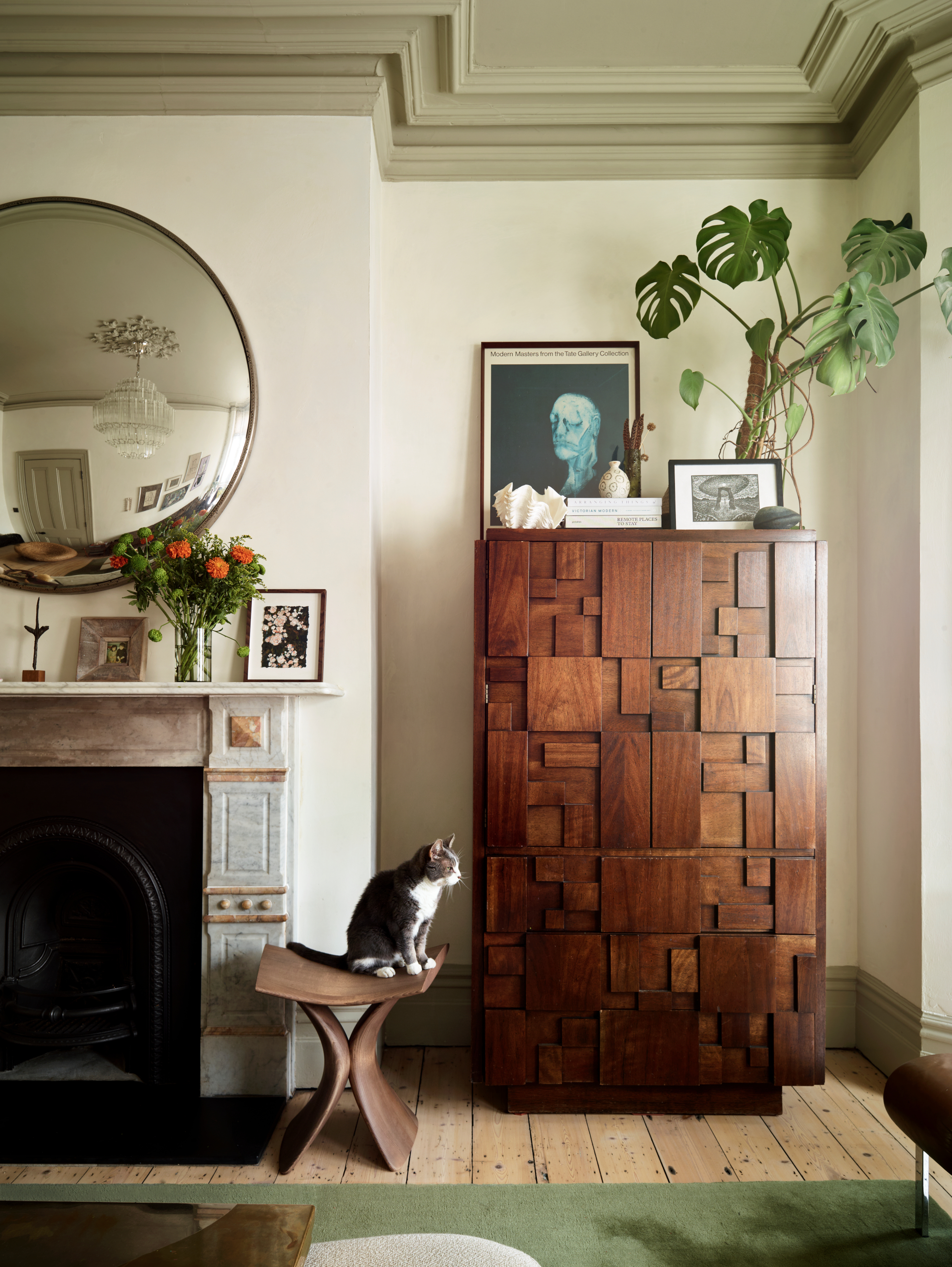 Corner of the living room with dark wood cabinet, green rug, pale olive painted ceiling and off-white walls