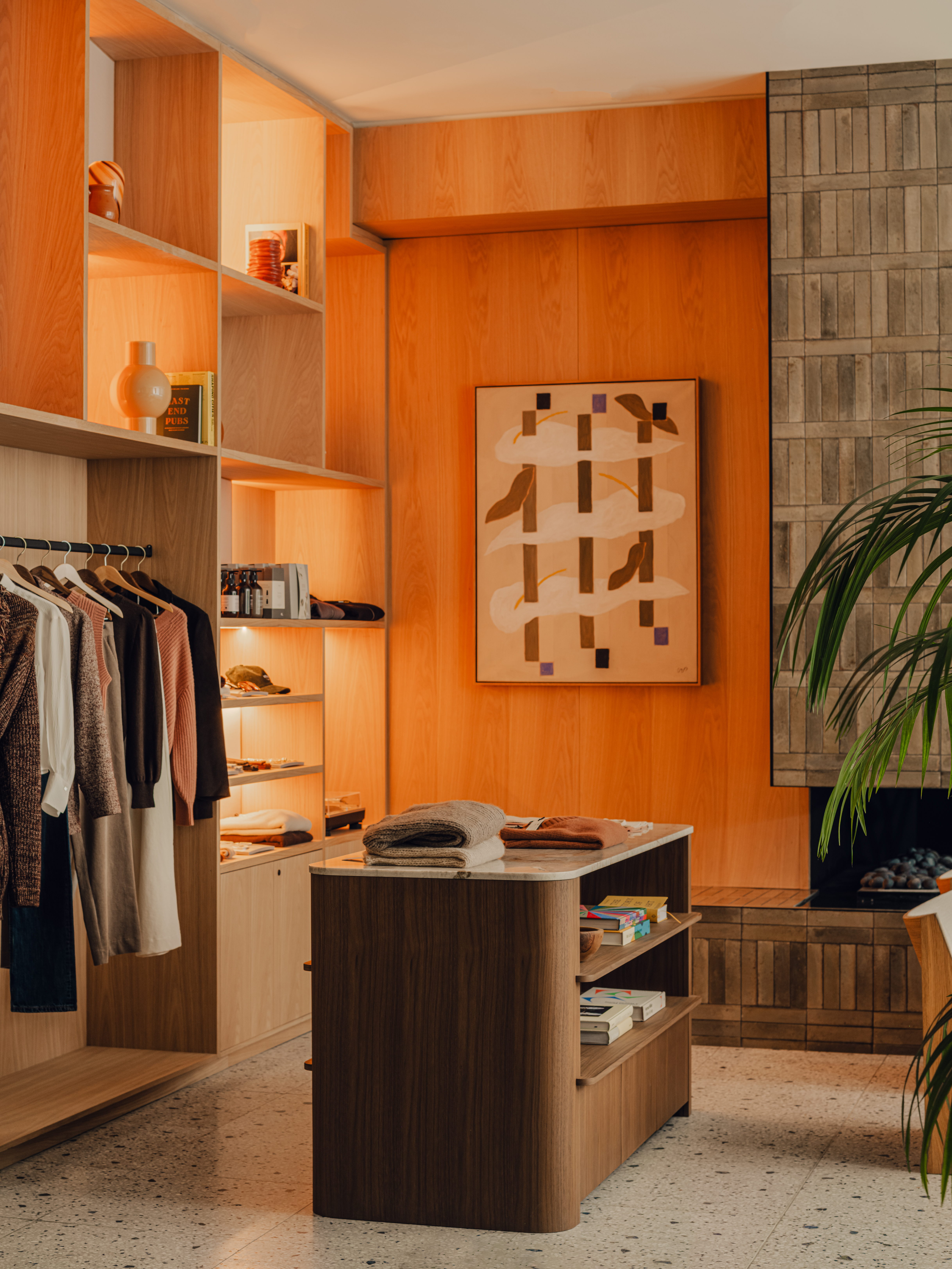 A hotel decorated with earthy hues, textural fabrics, sculptural wooden furniture with upholstered surfaces, thriving plants, abstract artworks, and warm lighting.