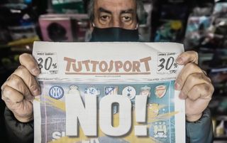 A newsagent holds up the front cover of Tuttosport, which protests against the European Super League