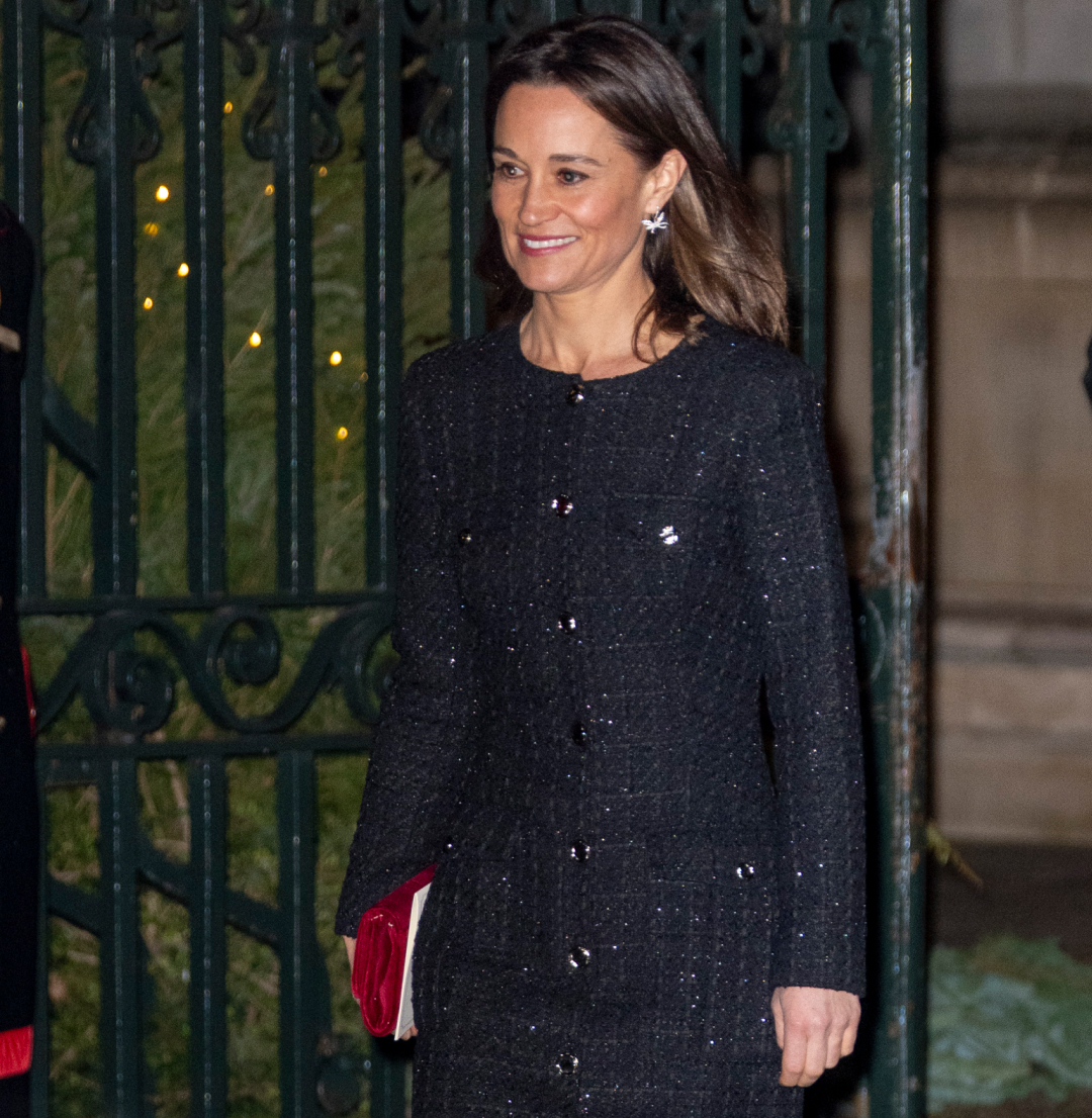Pippa Middleton wearing a black coat walking in front of a gate