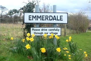 Emmerdale sign with daffodils growing around it