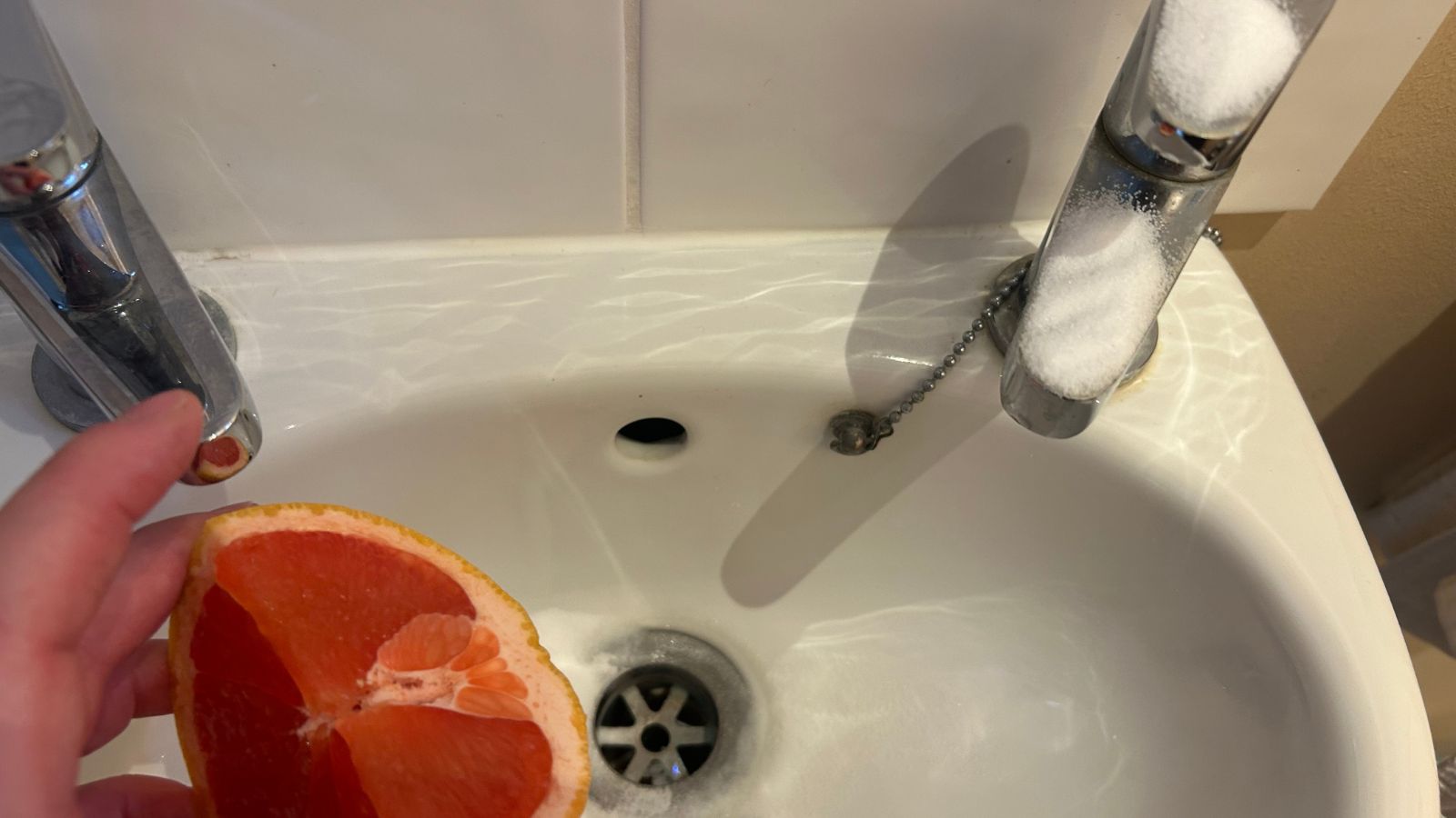 Facuet with salt on, holding a grapefruit over sink
