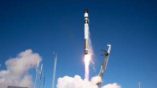 a white rocket launches into a blue sky