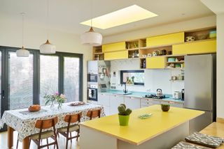 open plan kitchen diner with yellow cabinets, yellow worktop and glazing