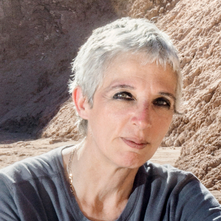 a person with short-cropped silver hair outside in a desert canyon