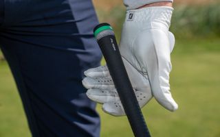 A golfer gripping a club with their left hand