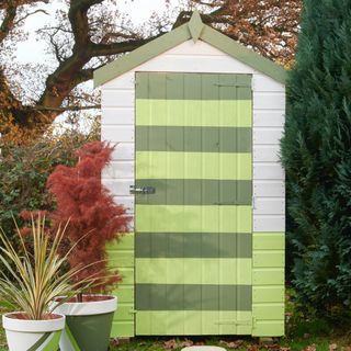 Garden shed painted in green stripes