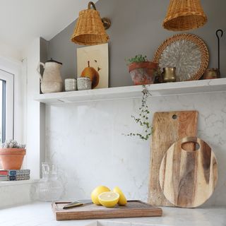 Kitchen with a marble worktop and backsplash, wooden cutting boards and rattan lampshades