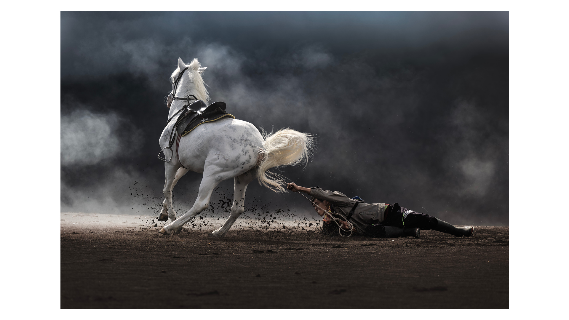 Photograph taken by Partha Pratim Roy at Mount Bromo, Jawa Timur, Indonesia, of an Indonesian horseman struggling to control his horse on the windswept sands. Winner, Best Single Image in Faces, People, Cultures Portfolio, Travel Photographer of the Year 2024.