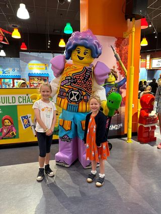 Ella and Mara having their picture taken with a Lego character