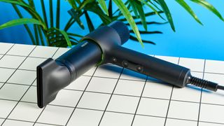 the heist 3.0 men's hair dryer in black with a bright green ring and magnetic attachment photographed against a blue background