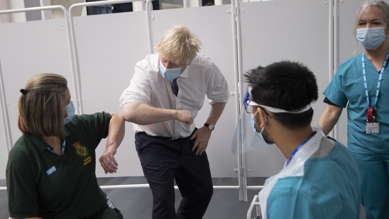 Boris Johnson bumps elbows with a first responder as she gets her vaccination