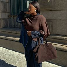 Influencer @nnennaechem wears a navy pinstripe suit with a brown scarf and brown suede tote.
