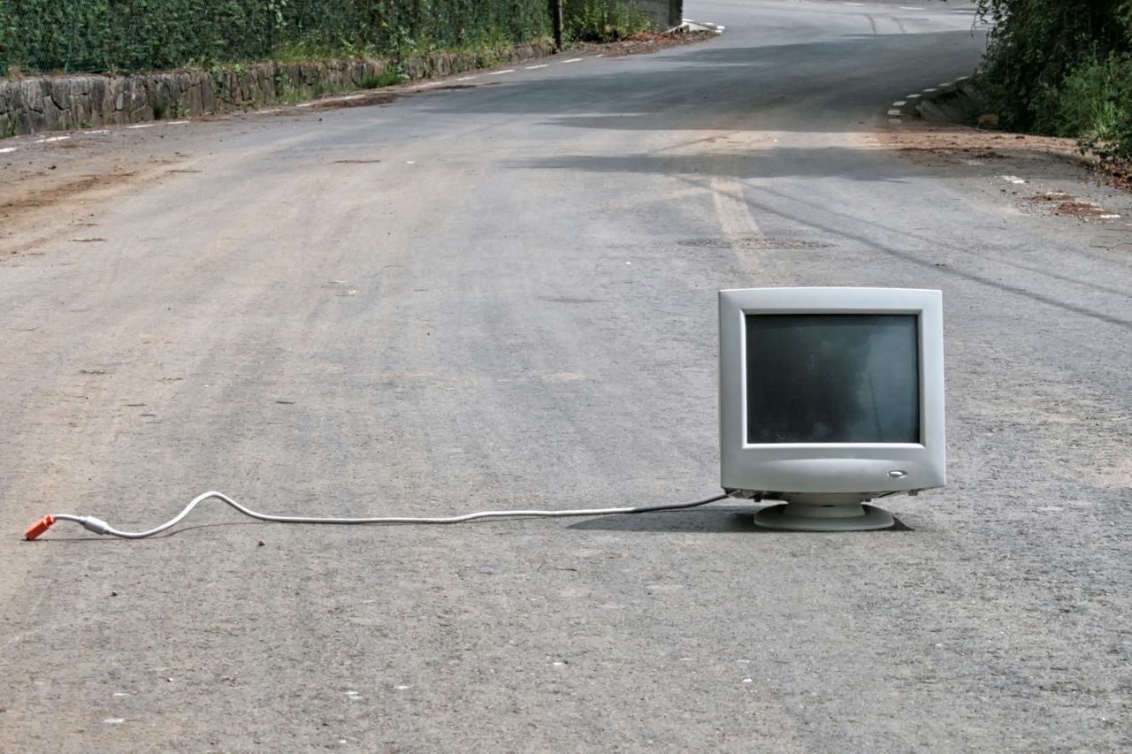 unplugged desktop computer sitting out in the middle of a road