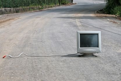 unplugged desktop computer sitting out in the middle of a road