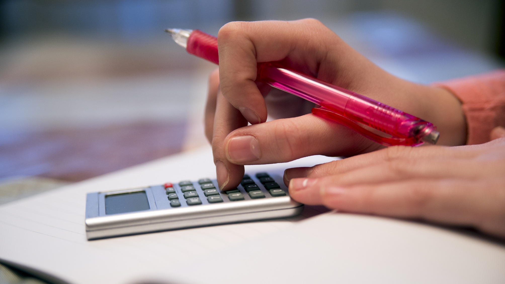 A teen girl uses a calculator, only her hands showing.
