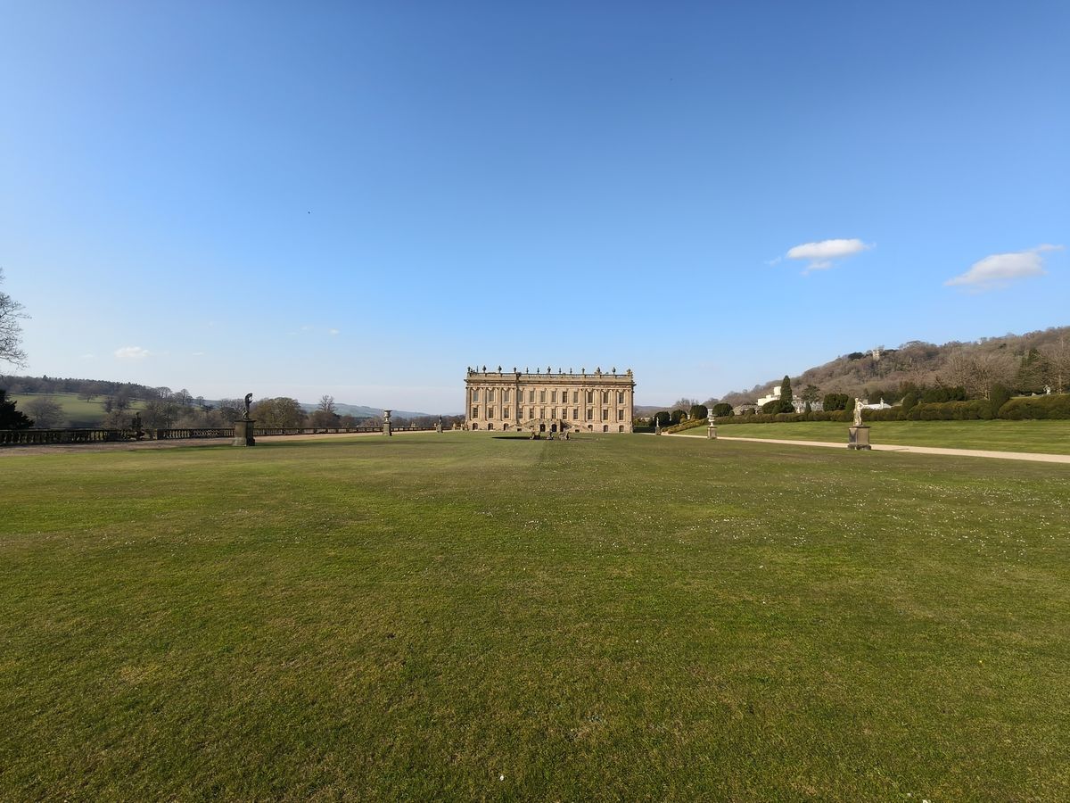A large house seen from far away across. a green field
