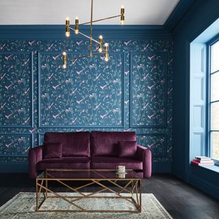 Graham & Brown wallpaper of the year Tori over wall panelling with purple velour couch and modern coffee table