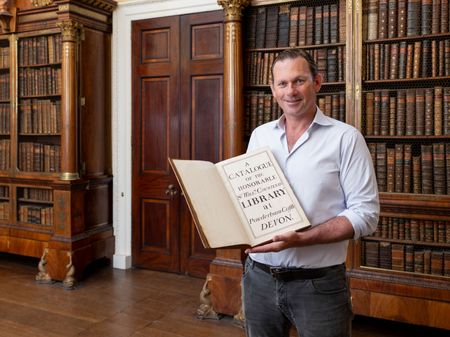 Charlie Courtenay, 19th Earl of Devon with his ancestor's book at Powderham Castle.