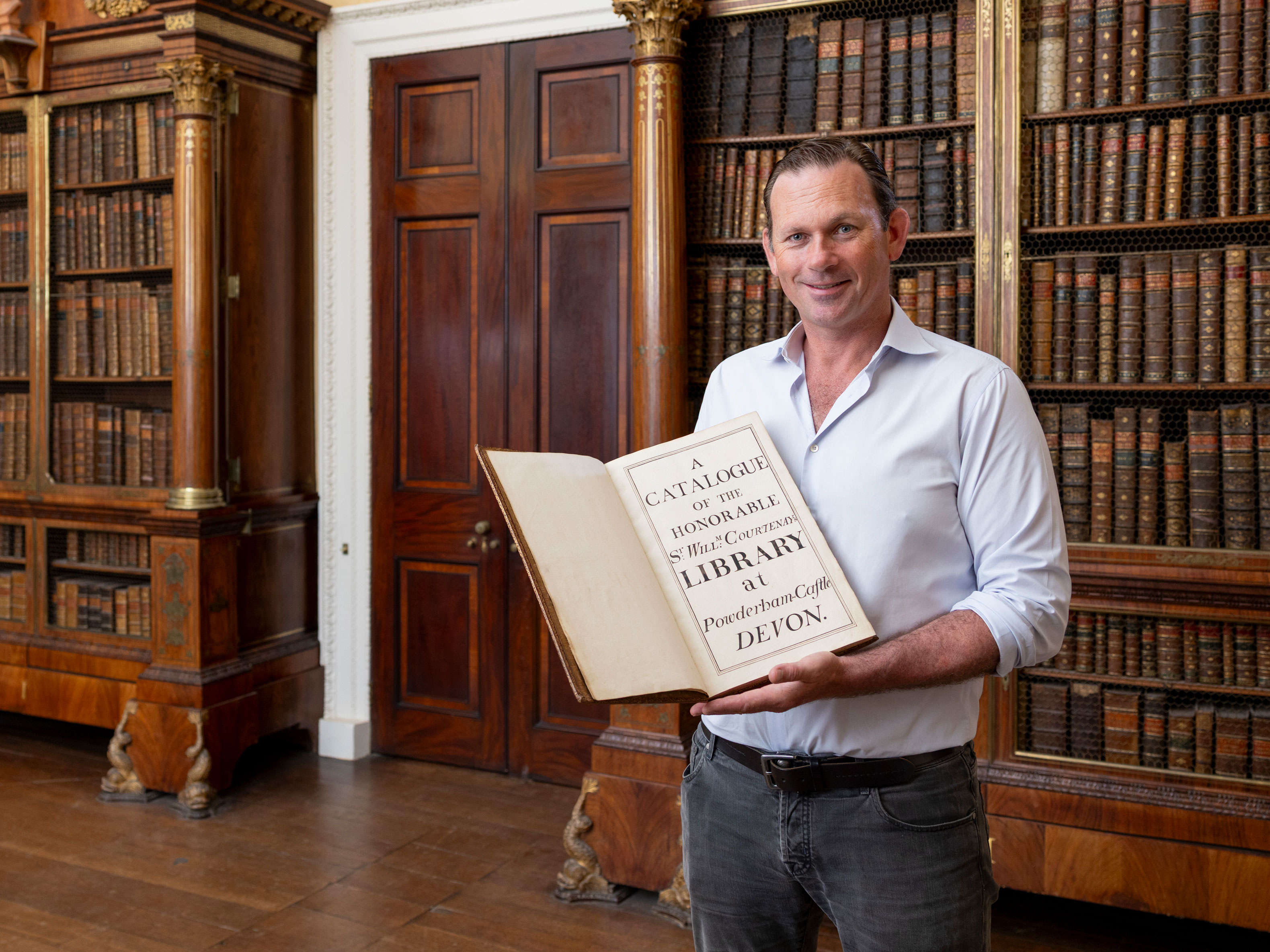 Charlie Courtenay, 19th Earl of Devon with his ancestor's book at Powderham Castle.