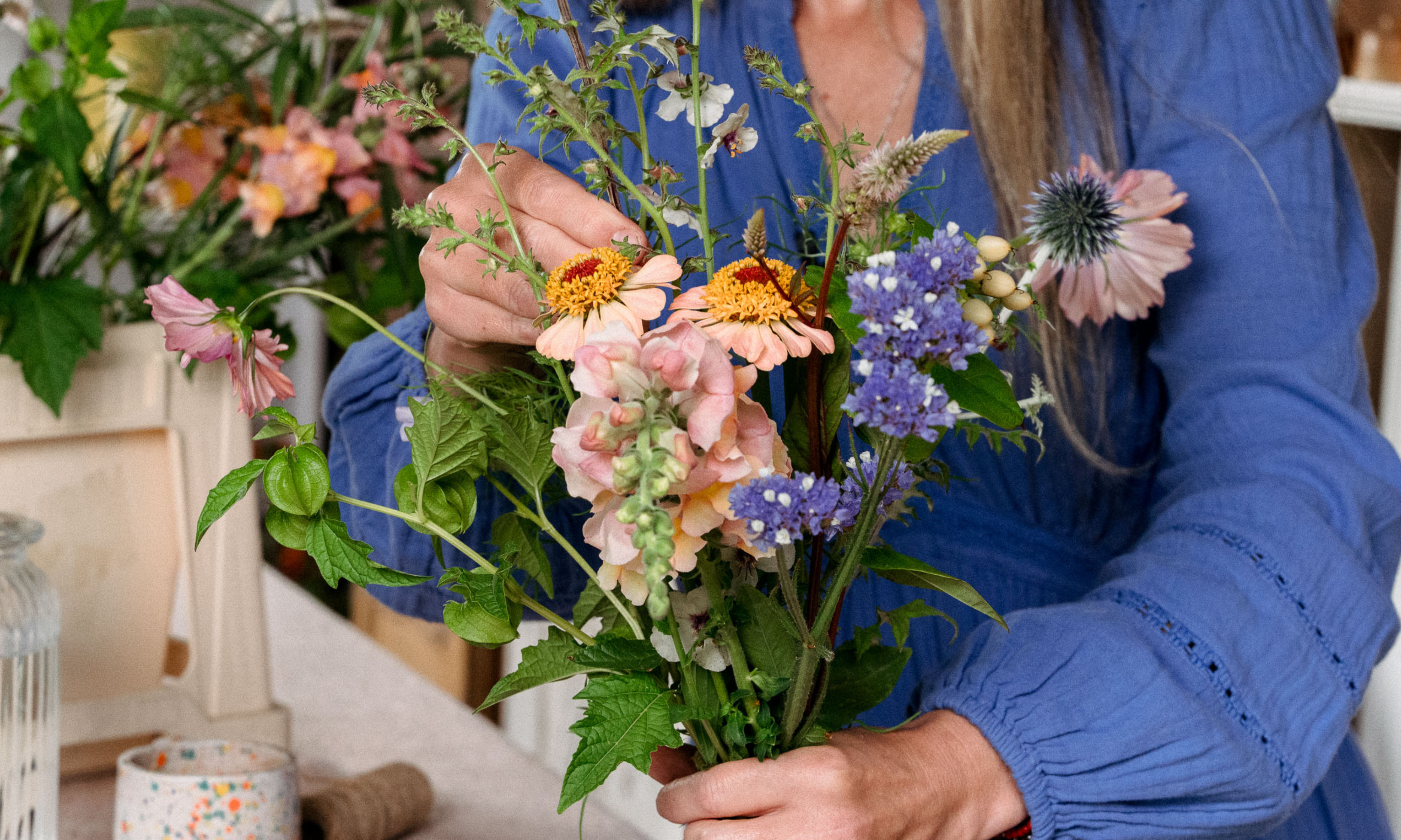woman in blue dress creating floral bouquet in the hand