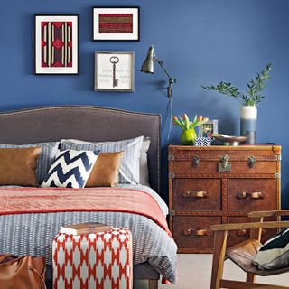 blue wall bedroom with grey bed and wooden drawers
