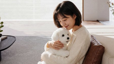 Ecovacs LilMilo robot dog with woman holding it in lifestyle setting