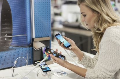 Woman comparing two smartphones in a shop