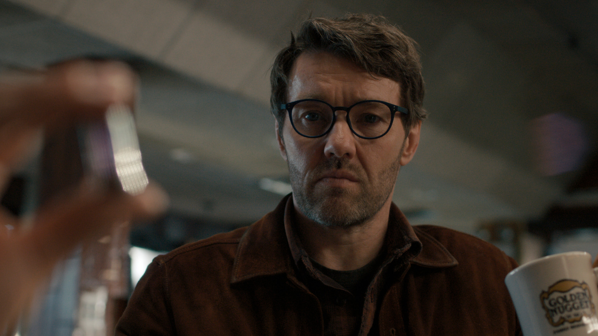 a bearded man with glasses stares intently
