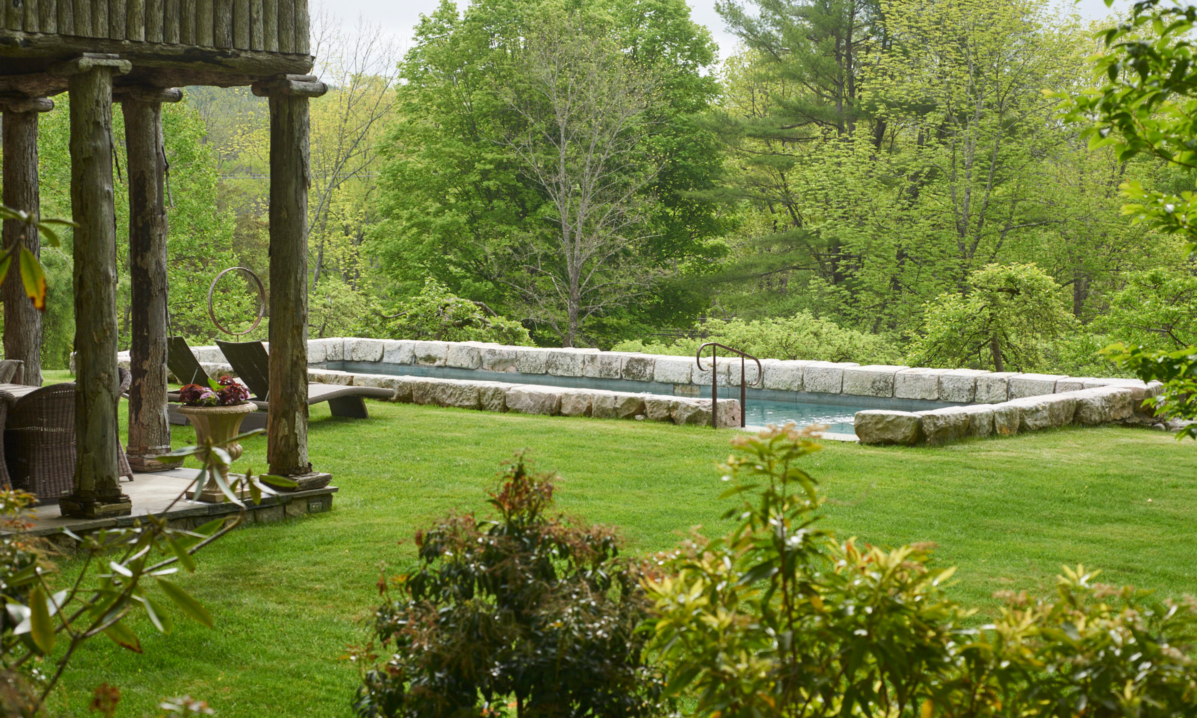Stone garden pool surrounded by lush lawn and mature trees