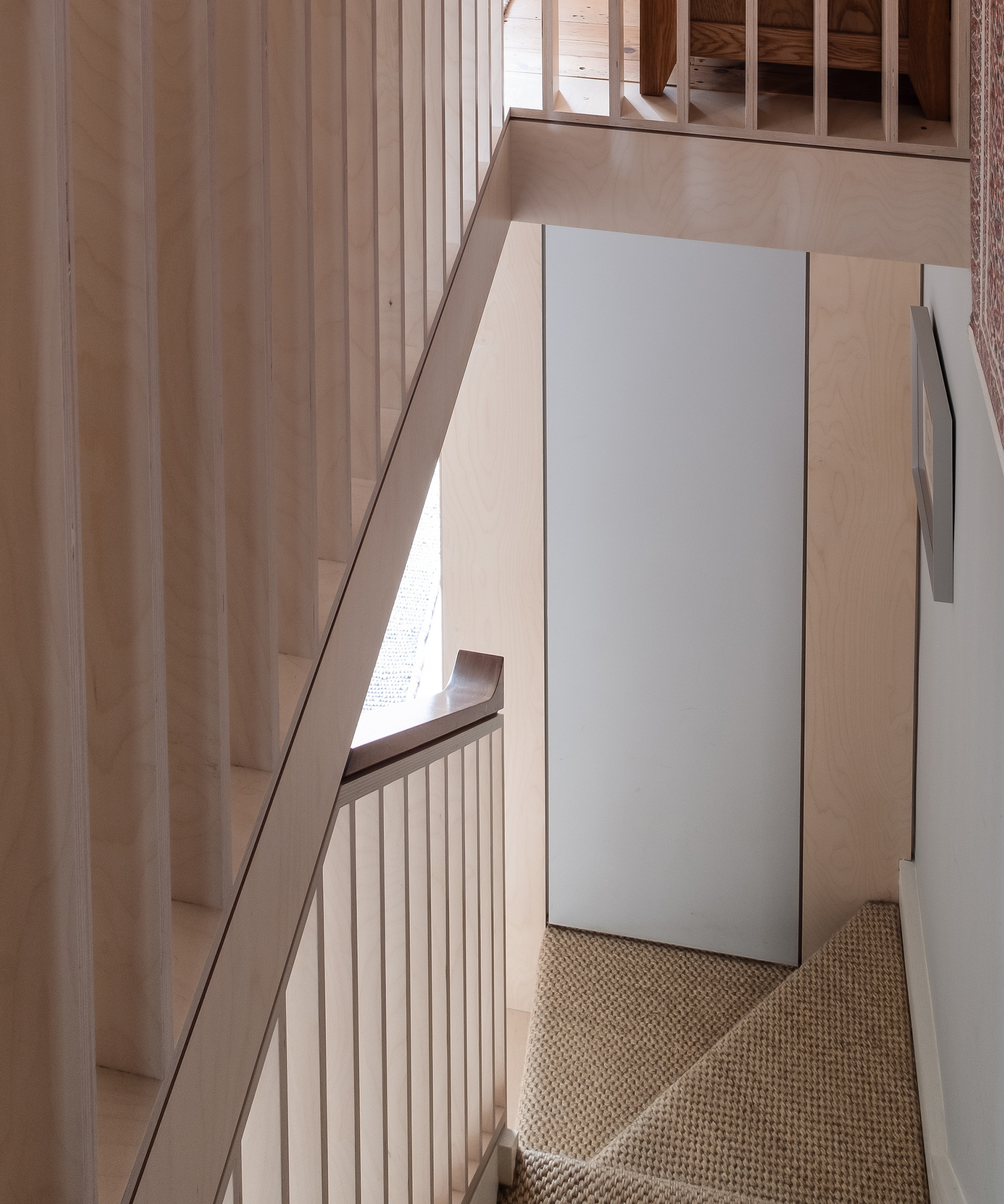 A narrow staircase in a Victorian terrace with plywood details