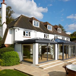 A large conservatory extensions with glass sliding doors on a large white house