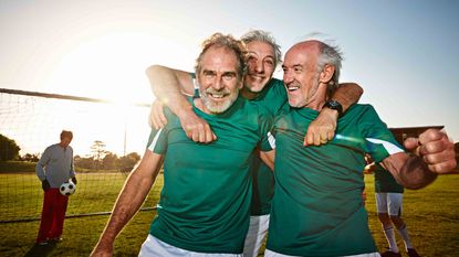 Three senior male soccer players celebrating