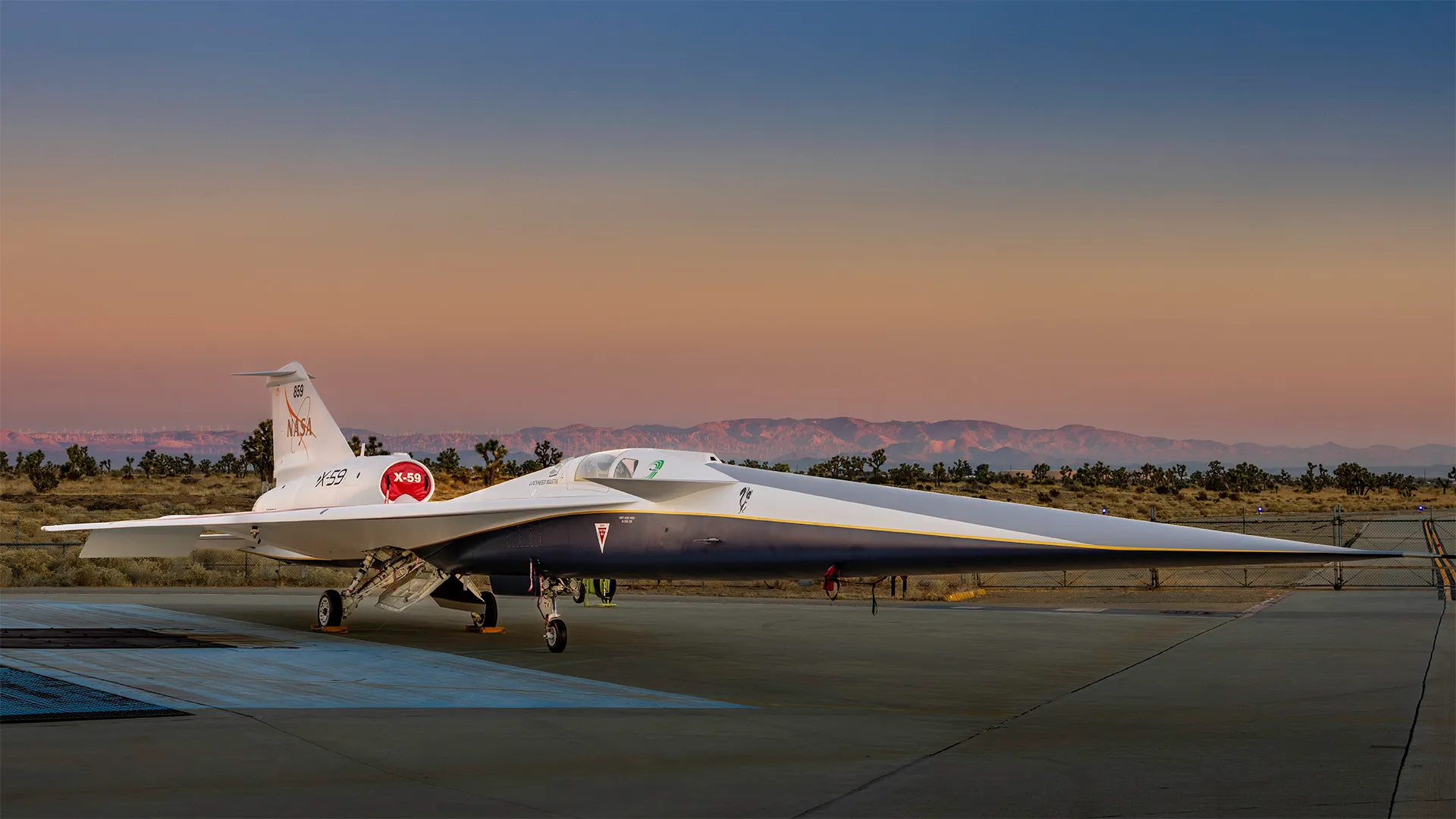 an elongated blue-and-white jet with a colorful sunrise behind it