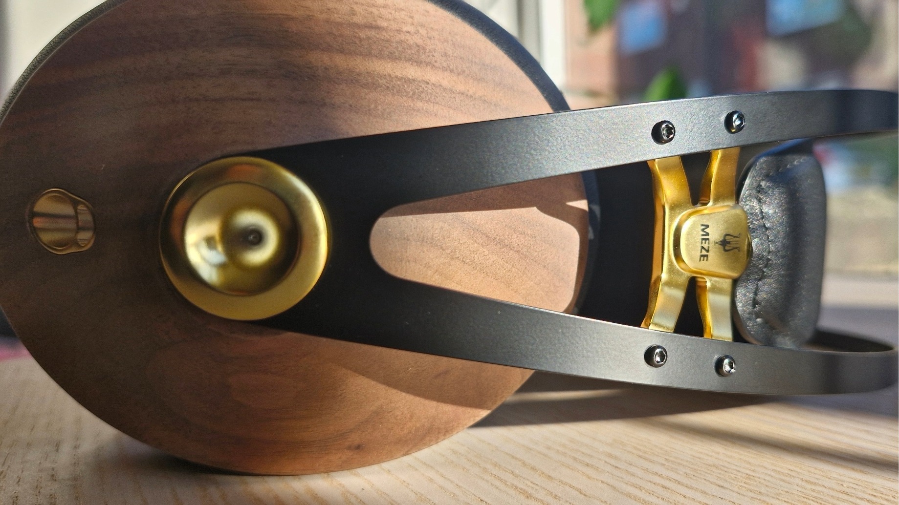 Earcups of the Meze Audio 99 Classics 2nd Gen over-ear headphones, laid down on their side on a wooden table