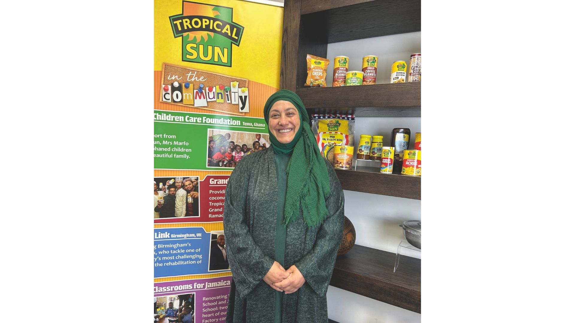 Saira Begum standing beside shelves of food bank donations
