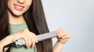 A woman straightening her hair with a hair straightener