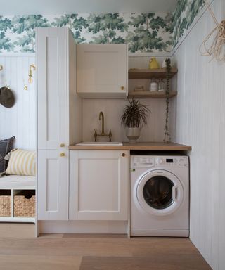 a neutral laundry room with green and white wallpaper, and an entryway bench to the left