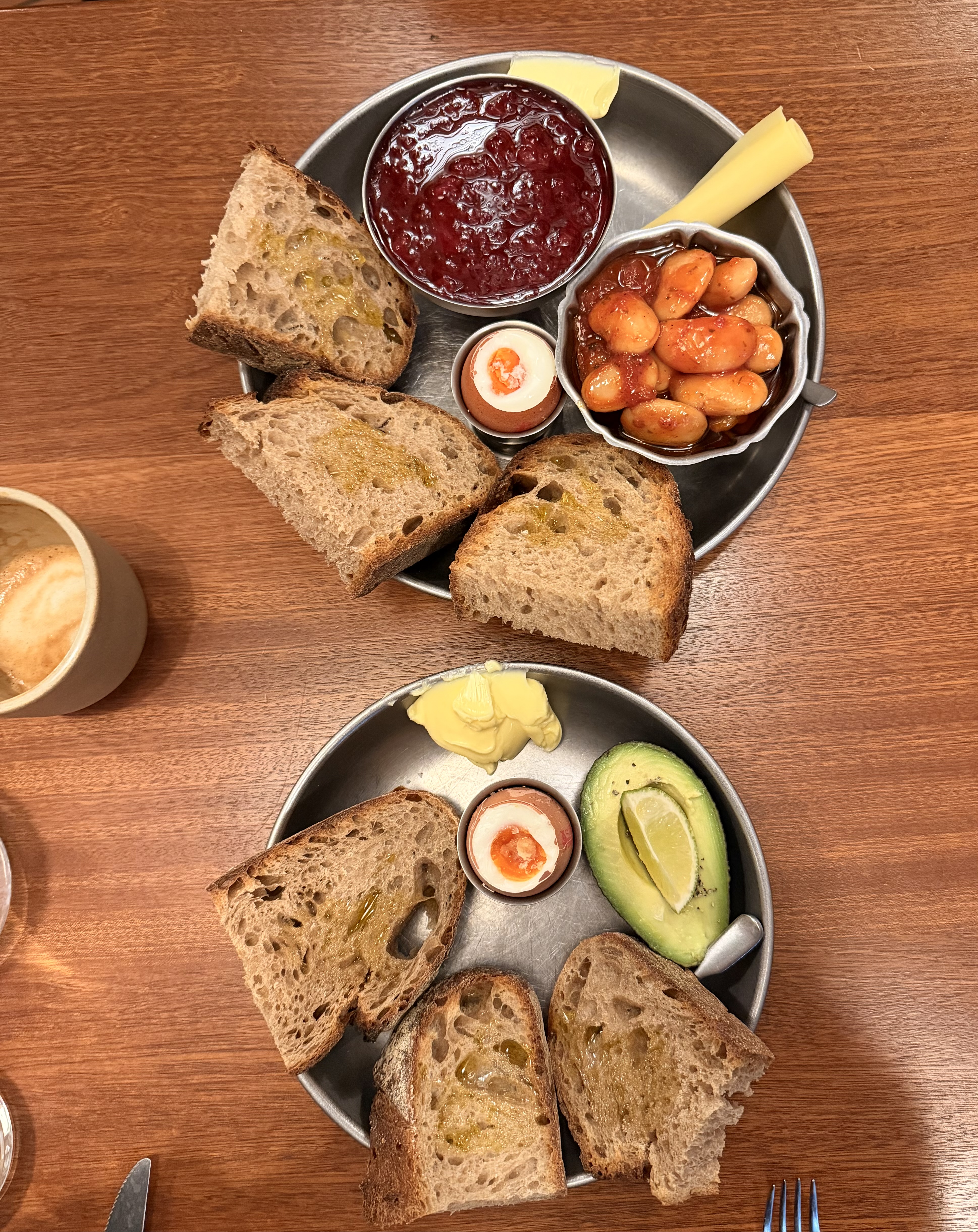Two breakfast bowls of boiled eggs, sourdough, avocado and butter beans
