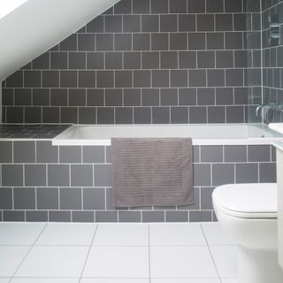 Bathroom with white floor tiles and grey tiles on bath and walls