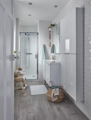 A white bathroom idea designed by B&Q with wooden stool and gloss bathroom units