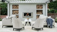 A patio with an outdoor fireplace and modern built in log store