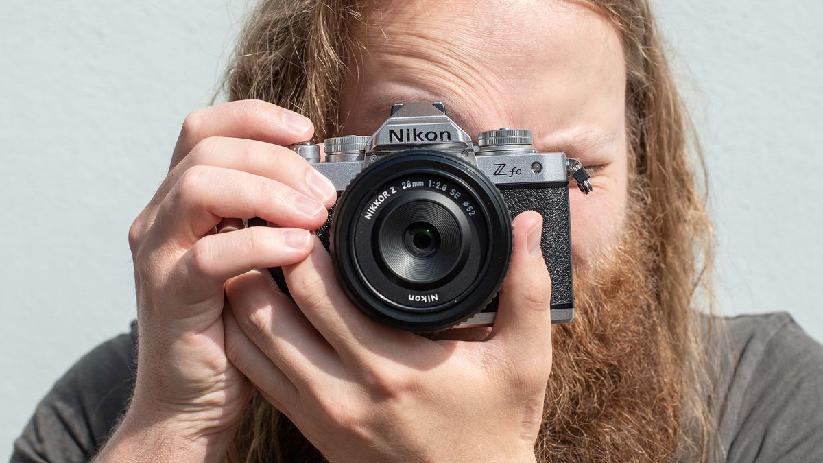 Man holding the Nikon Z fc camera up to his face